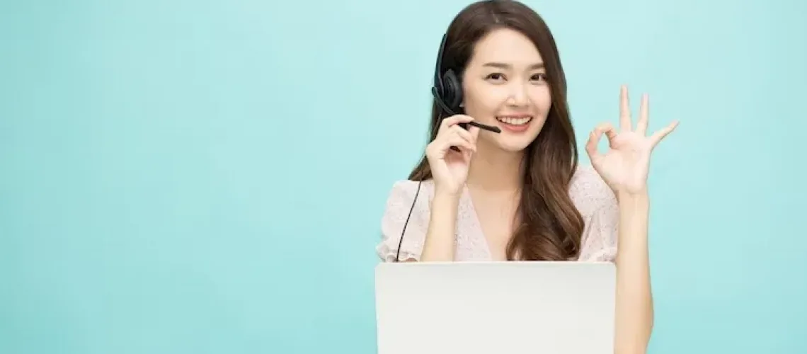 young-asian-woman-friendly-operator-agent-with-headsets-showing-ok-sign-working-light-green-backgrou